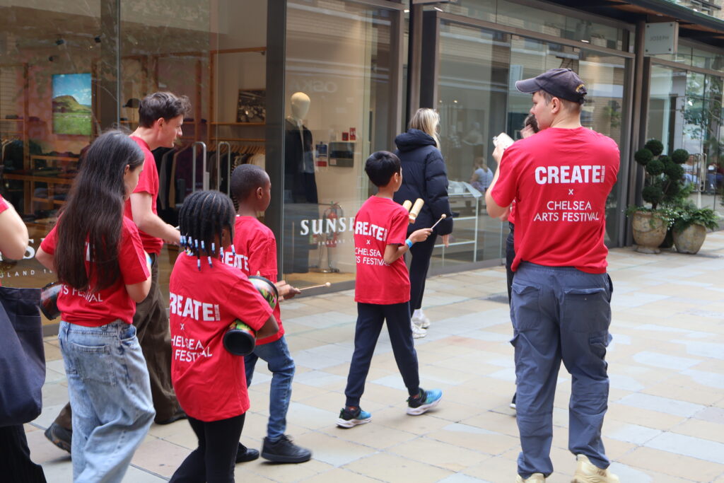 Young carers performing on the street at Chelsea Arts Festival 2026.
