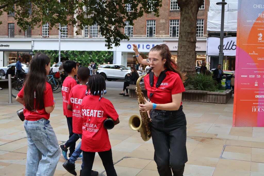 Young carers performing on the street at Chelsea Arts Festival 2026.
